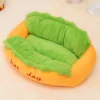 Cozy hot dog-shaped pet bed with plush green lining, resting on a soft white sheet.