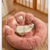 A relaxed cat lounging in a soft pink paw-shaped bed, enjoying a lazy day in a cozy room.
