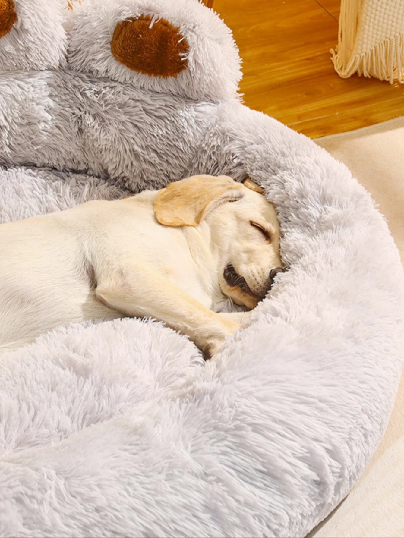 Labrador puppy blissfully asleep on a luxurious grey paw-shaped bed, embodying pet comfort at its finest.